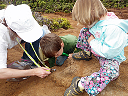 Dr. Bishop with her kids examining altered volcanic rocks in the field