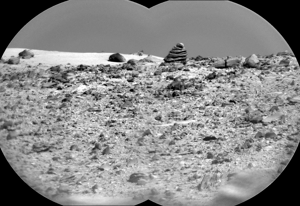 black and white image of a cone shaped rock on the surface of mars.